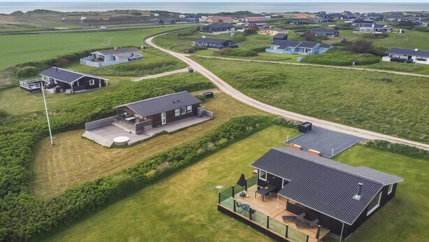 An aerial view of a coastal residential area with houses, a winding road, and a grassy field. - "Lok" - 450m from the sea by Interhome (Løkken)