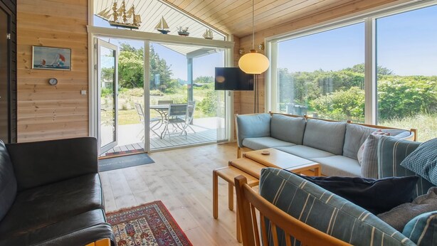 Un vaste espace de vie doté d’un plafond en bois, de grandes fenêtres, d’un canapé, d’une table basse et d’un téléviseur.