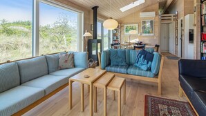 Un salon moderne avec une grande fenêtre, un canapé, une table basse et une cheminée.