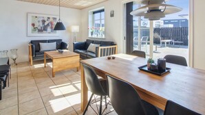 Una sala moderna con techo de madera, un comedor con una mesa larga y un gran ventanal con vistas al exterior.