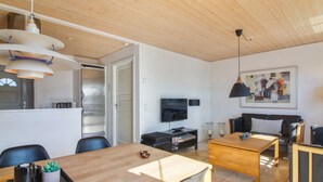 Una sala de estar moderna con techo de madera, un comedor con mesa de madera y un sofá.