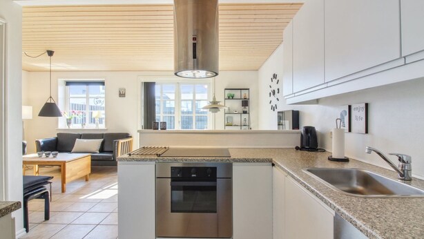 Una cocina moderna con lavavajillas integrado, un ventanal grande y una zona de comedor con mesa y sillas.