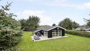 A modern black house with a large garage, a patio with two lounge chairs, and a well-maintained lawn. - "Into" - 400m from the sea by Interhome (Løkken)