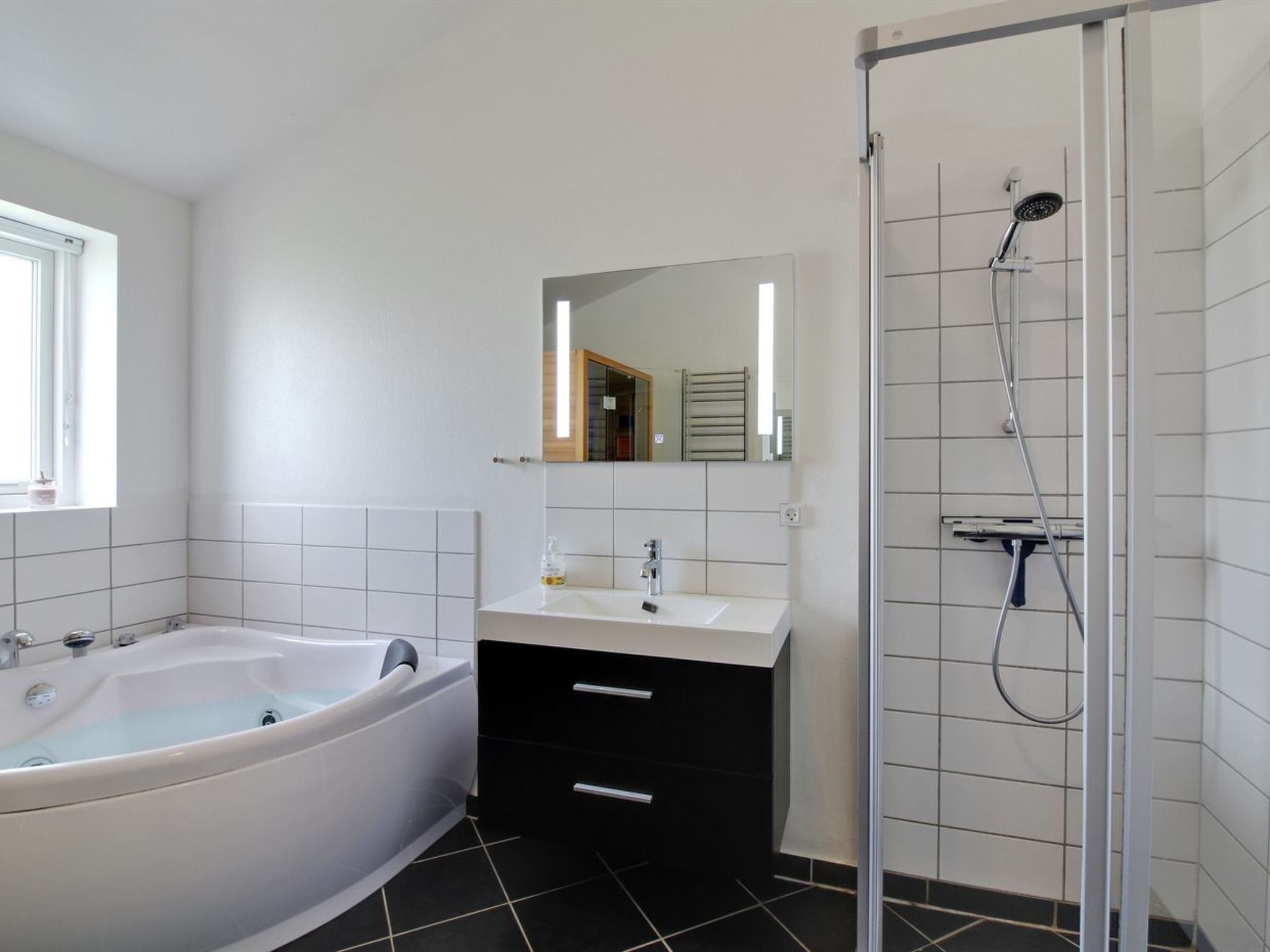 A modern bathroom with a bathtub, a sink, a mirror, and a shower.
