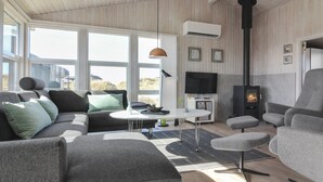Ein modernes Wohnzimmer mit einer Couch, Sesseln, einem Couchtisch und einem Kamin.