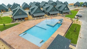 A resort with multiple chalet-style buildings, a central swimming pool, and a view of a lake. - Lakeview! Indoor Pool! Pool Table! (Hollister)