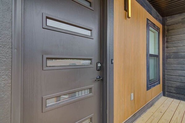A modern exterior with a grey door, a wooden door frame, and a small window.