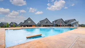 Une piscine sous un ciel bleu azur, entourée de bâtiments modernes aux toits inclinés.