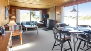 Una habitación acogedora con techo de madera, un sofá, una mesa de comedor con sillas, un televisor y una chimenea.