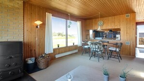 Interior acogedor de una cabaña con chimenea, paredes de madera, comedor y cocina.