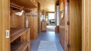 Un pasillo interior de madera con un adorno de pájaro colgante, un espejo y vista hacia un comedor.