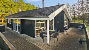 Ett modernt hus med en täckt uteplats, en skorsten och en terrass.