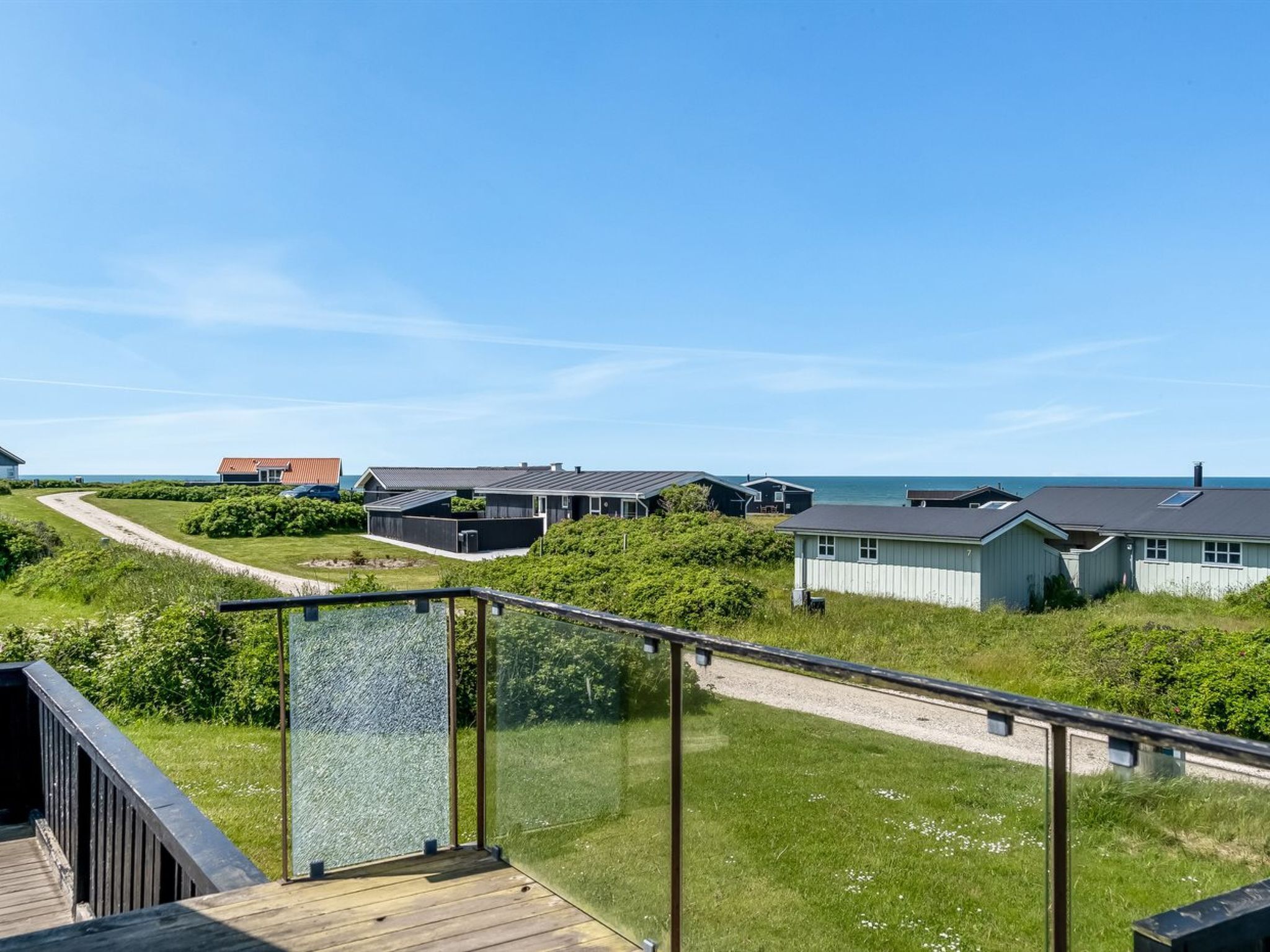 Una propiedad costera con varias casas, cielo despejado y vista al mar.