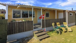 Une maison de plain-pied avec un porche, un drapeau et des sièges d’extérieur.
