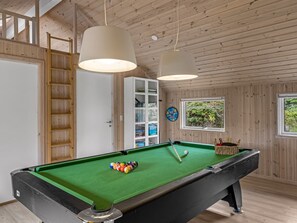 Une table de billard avec des billes, un jeu de fléchettes et une fenêtre donnant sur un paysage verdoyant.