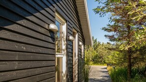 A wooden house with a gravel pathway leading to the entrance, surrounded by greenery. - "Federica" - 500m from the sea by Interhome (Løkken)