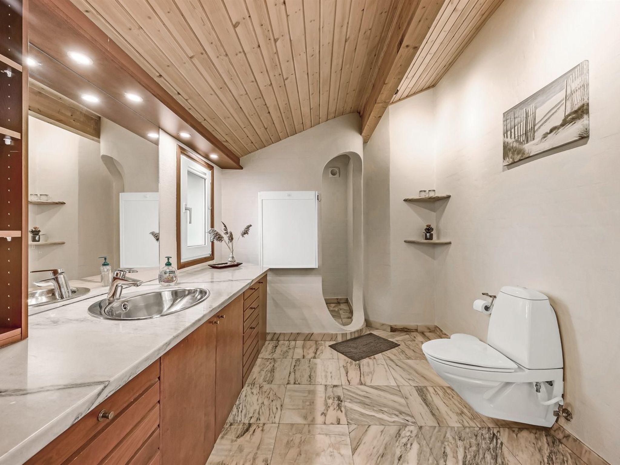 A modern bathroom with a wooden ceiling, marble flooring, a double sink, a toilet, and a shower.