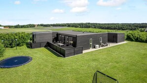 A modern house with a patio, a swimming pool, and a tennis court.