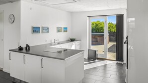 A modern kitchen with a large island, a dining area, and a sliding glass door to a patio.