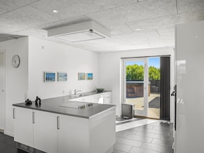 A modern kitchen with a large island, a dining area, and a sliding glass door to a patio.
