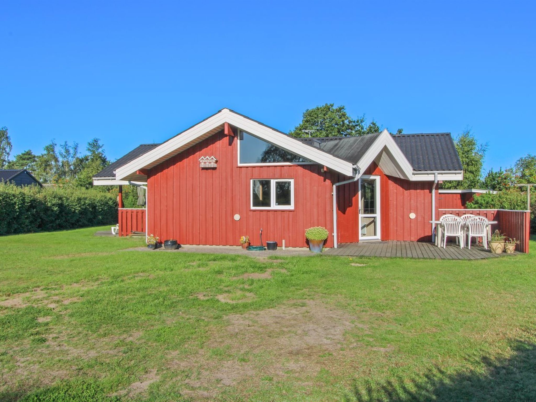 A red house with a white roof, a front porch, and a small deck.
