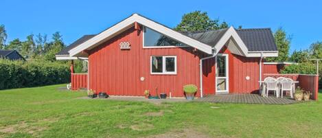 A red house with a white roof, a front porch, and a small deck.