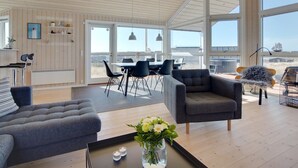 A spacious living area with a high ceiling, large windows, and a view of the sea.