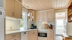 A modern kitchen with wooden cabinets, a built-in oven, a dishwasher, and a coffee maker.