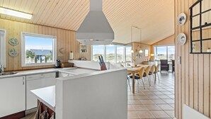 A modern kitchen with wooden walls, a large island, and a view of the outdoors.