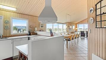 Une cuisine moderne avec des murs en bois, un grand îlot central et une vue sur l’extérieur.