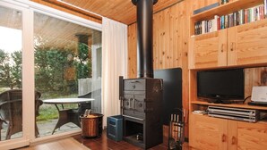 Eine moderne Küche mit Holzofen, Essbereich mit Tisch und Stühlen sowie ein Fernseher auf einem Holzschrank.