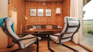 Ein gemütliches Zimmer mit Holzwänden, einer Holzbalkendecke, einer Couch, zwei Relaxliegen, einer Lampe und gerahmten Bildern von London und New York.