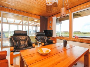Uma sala de estar moderna com poltronas de couro, uma mesa de madeira e uma televisão.