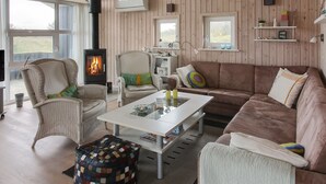 A cozy living room with a fireplace, wicker furniture, and a view of the outdoors.