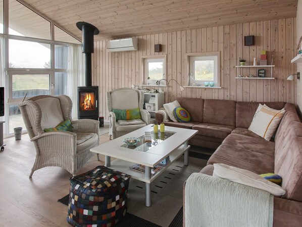 A cozy living room with a fireplace, wicker furniture, and a view of the outdoors.