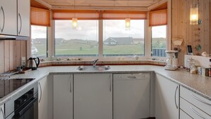 A kitchen with a large window, a dishwasher, and a stove.