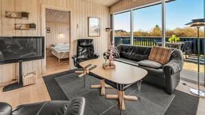 A cozy room with a TV, leather furniture, a large window, and a view of the outdoors. - "Benjamina" - 530m to the fjord by Interhome (Tarm)