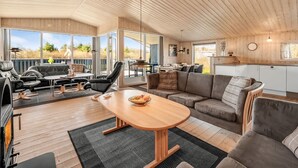 A spacious living area with a wooden ceiling, a large round table, and a sofa. - "Benjamina" - 530m to the fjord by Interhome (Tarm)