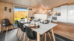 A modern kitchen with white cabinets, a large island, and a dining area with a long table and chairs. - "Benjamina" - 530m to the fjord by Interhome (Tarm)