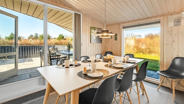 A modern dining area with a large table, black chairs, and a view of the outdoors. - "Benjamina" - 530m to the fjord by Interhome (Tarm)