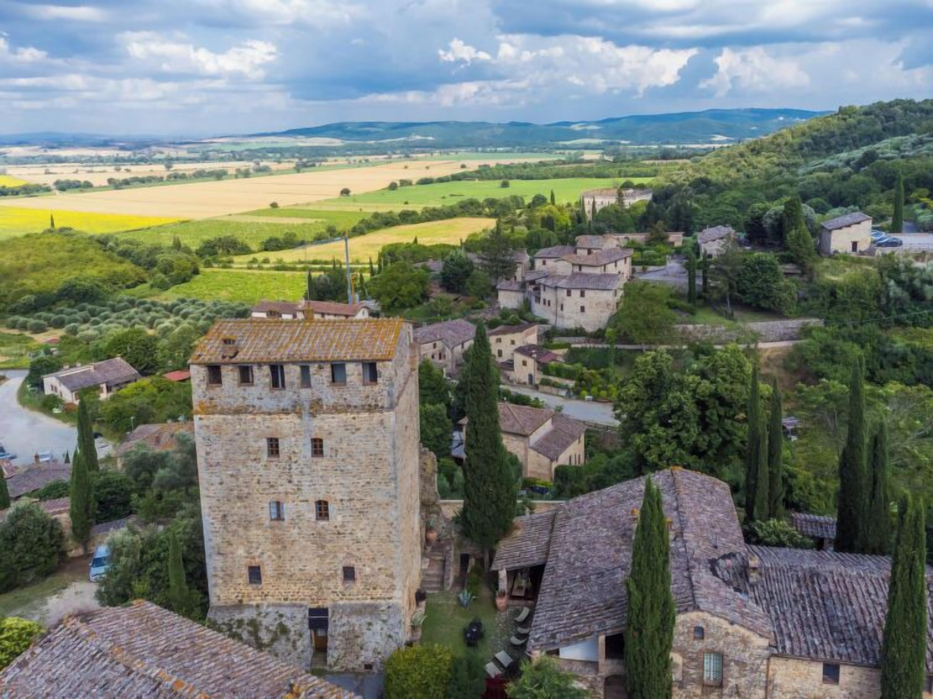 A historic stone building with a tower, surrounded by lush greenery and traditional architecture.