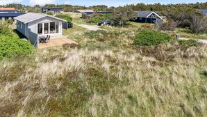 Une propriété située en bord de mer, comprenant une petite maison dotée d’une terrasse et d’un espace patio.