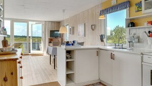 Une cuisine moderne avec des meubles blancs, une grande fenêtre et une vue sur l’extérieur.