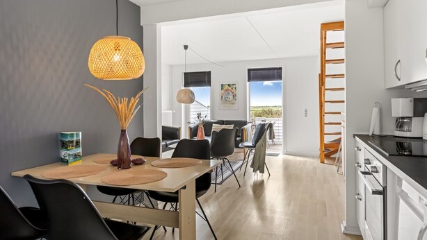 A modern kitchen with white cabinets and a dining area with a wooden table and black chairs. - "Drita" - 2.3km from the sea by Interhome (Rømø)