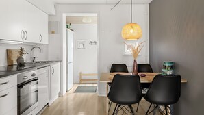 A modern kitchen with white cabinets, a built-in oven, and a dining area with a wooden table and black chairs. - "Drita" - 2.3km from the sea by Interhome (Rømø)