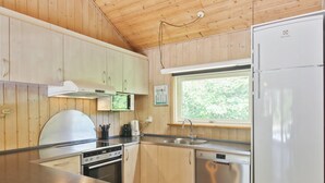 A compact kitchen with wooden cabinets, a stainless steel dishwasher, a built-in oven, and a window providing natural light. - "Thordo" - 2.4km from the sea by Interhome (Rømø)