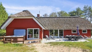 A red barn-style building with a thatched roof, a patio with outdoor furniture, and a wooden deck. - "Thordo" - 2.4km from the sea by Interhome (Rømø)