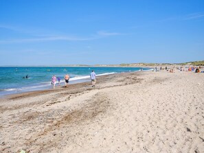 Une plage de sable où l’on voit des gens se promener et nager.