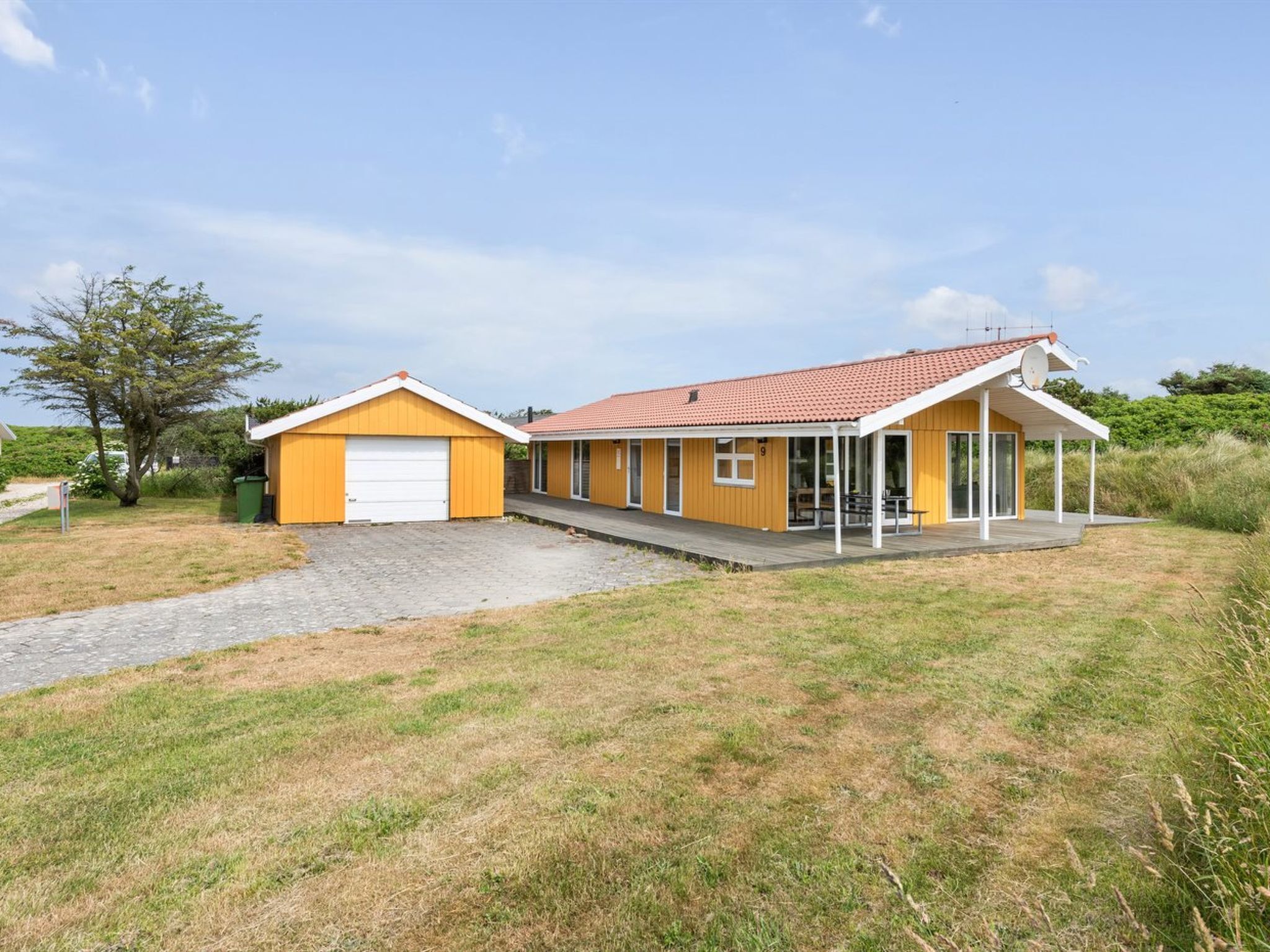 Un bâtiment jaune à deux étages, doté d’un patio couvert et d’un garage.