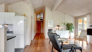 A spacious living area with a wooden floor, a dining table, a sofa, and a TV.